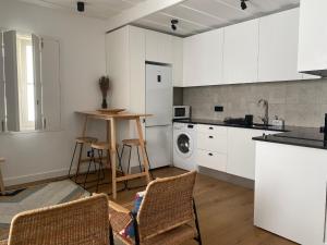 a kitchen with white cabinets and a table and chairs at Grândola Suites - Suite Afonso in Grândola