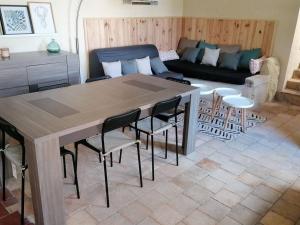 uma sala de estar com uma mesa e cadeiras e um sofá em Maison chaleureuse avec cheminée em Bourgueil