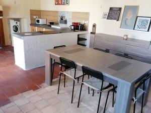 uma mesa e cadeiras numa cozinha com um balcão em Maison chaleureuse avec cheminée em Bourgueil
