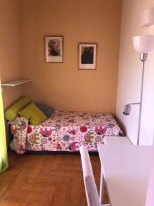 Familia Anfitriona acoge terraza في إشبيلية: غرفة نوم صغيرة مع سرير وبطانية مزهرة
