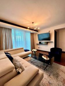 ein Wohnzimmer mit einem Sofa und einem Flachbild-TV in der Unterkunft Merendon Heights Luxury Condo in San Pedro Sula