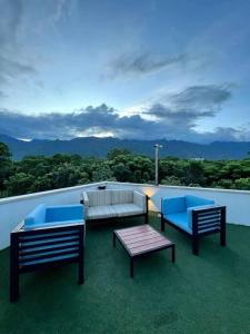 einen Balkon mit 3 Stühlen, einem Sofa und einem Tisch in der Unterkunft Merendon Heights Luxury Condo in San Pedro Sula