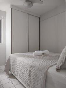 um quarto branco com uma cama grande e lençóis brancos em Apartamento de 2 quartos no Recife