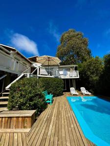 a house with a wooden deck and a swimming pool at Gran casa en Isla Negra in Isla Negra