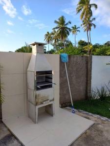 an outdoor oven with a mop next to a wall at Casa de Praia em Condomínio Fechado em Alagoas! in Paripueira