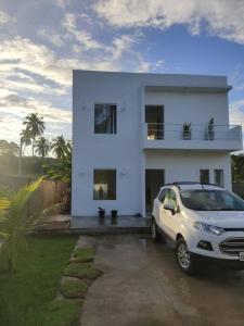 um carro estacionado em frente a uma casa branca em Casa de Praia em Condomínio Fechado em Alagoas! em Paripueira