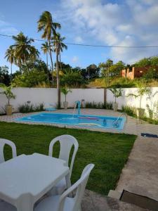 uma piscina com uma mesa branca e cadeiras num quintal em Casa de Praia em Condomínio Fechado em Alagoas! em Paripueira