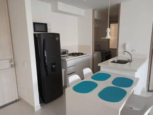 eine Küche mit einem schwarzen Kühlschrank und weißen Schränken in der Unterkunft Apartamento en Ricaurte Cundinamarca in Ricaurte