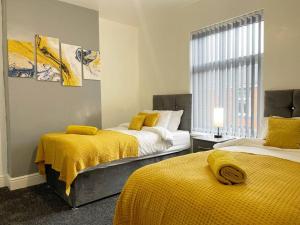 two beds in a room with yellow blankets at Cliff House By RMR Accommodations - NEW - Sleeps 8 - Modern - Parking in Stoke on Trent