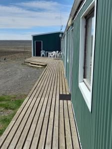 una terraza de madera en el lateral de un edificio verde en Áfangi en Blönduós