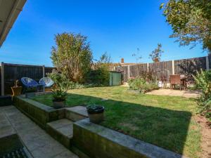a backyard with a fence and a yard with a patio at Honeybees Haven in Hunstanton
