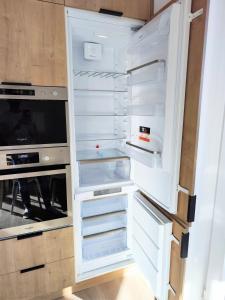 an empty refrigerator with its door open in a kitchen at Quietly oriented apartment with free parking and balcony in Bratislava