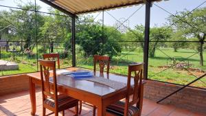 a wooden table and chairs on a patio with a large window at La casita del lago in Ypacarai