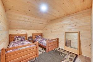 two beds in a cabin with wooden walls at Serene Centre Hall Cabin with Stream On-Site! in Centre Hall