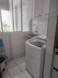 uma cozinha branca com uma máquina de lavar roupa e um lavatório em Apartamento de 2 quartos no Recife