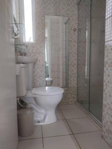 uma casa de banho com um WC e uma cabina de duche em vidro. em Apartamento de 2 quartos no Recife