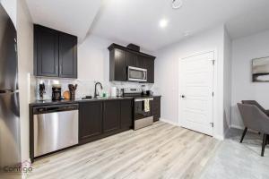 a kitchen with black cabinets and stainless steel appliances at The Obsidian, AC, Sleeps 14, Near YEG Airport in Edmonton