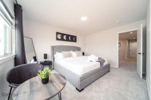 a bedroom with a bed and a table and a chair at The Obsidian, AC, Sleeps 14, Near YEG Airport in Edmonton