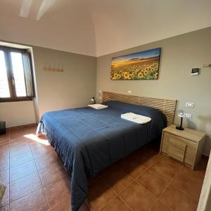 Un dormitorio con una cama azul y una pintura en la pared en Da Sciuri case vacanza Barisciano, en Barisciano