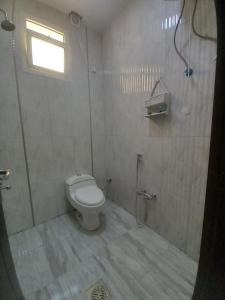 a bathroom with a toilet and a shower with a window at شقق مفروشة - توافيق in Buraydah