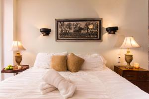 a white bed with two lamps and a picture on the wall at Garlands Del Rio in Puerto Vallarta