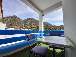 a table and chairs on a balcony with mountains at Balcon Bleu in Chefchaouene