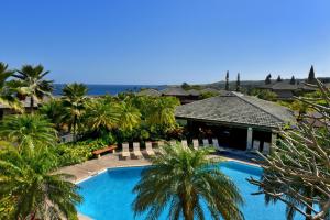 a swimming pool with palm trees and a building at Kapalua Ridge Villas 2612 in Kahana