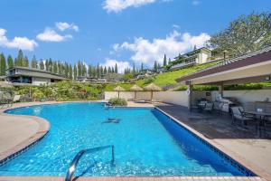 a large blue swimming pool with chairs and umbrellas at Kapalua Golf Villas 17T8 in Kahana