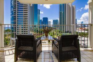 a balcony with a table and chairs and a view of the city at Home away from home 2 bdr Ocean views 1350AM in Honolulu