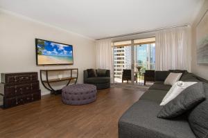 a living room with a couch and a tv at Home away from home 2 bdr Ocean views 1350AM in Honolulu