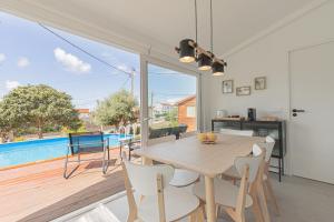 a dining room with a table and chairs and a pool at Casa Pinhão in Sesimbra