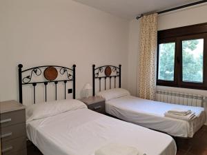 1 dormitorio con 2 camas y ventana en Casa rural villa de lupiana, en Lupiana