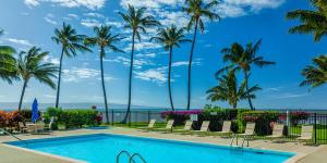 uma piscina com palmeiras e o oceano em Molokai Shores by HI em Kaunakakai
