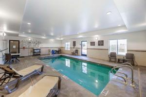a swimming pool with chairs and a table in a building at Sleep Inn & Suites Carlsbad Caverns Area in Carlsbad