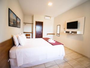 a hotel room with a white bed and a tv at Pousada Reobote in São Miguel do Gostoso +37 photos