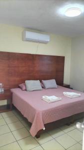 Elle comprend un grand lit avec des draps roses et des oreillers blancs. dans l'établissement Hotel La Estancia, à Río Verde