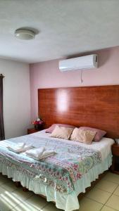 - une chambre avec un grand lit et une tête de lit en bois dans l'établissement Hotel La Estancia, à Río Verde