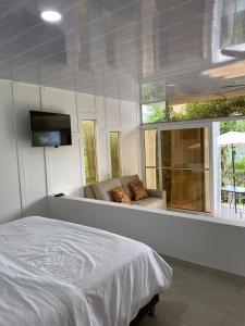 1 dormitorio con cama, sofá y TV en Cabañas Los Tulipanes, en La Mesa