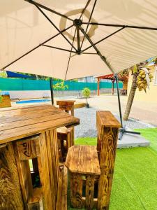 un tavolo di legno e una panca sotto un ombrello di Villa senseo a Capesterre-Belle-Eau