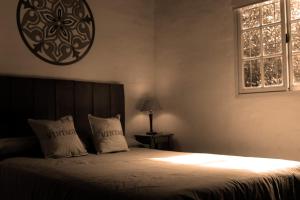1 dormitorio con 1 cama con 2 almohadas y ventana en Casa El Colibrí en Capilla del Monte
