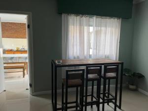 a kitchen with a bar with three stools in front of a window at Relax 6 in Paysandú
