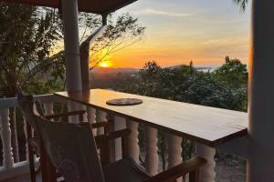une table sur un balcon avec vue sur le coucher de soleil en arrière-plan dans l'établissement Breathtaking Sea View house from your BED - 3 min to BEACH, à Koh Samui 