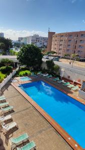 a large swimming pool with lounge chairs and a hotel at ALAMO LUXURY APARTMENT in Playa del Ingles