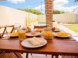drewniany stół z talerzami jedzenia i napojów na nim w obiekcie Pousada Reobote w mieście São Miguel do Gostoso
