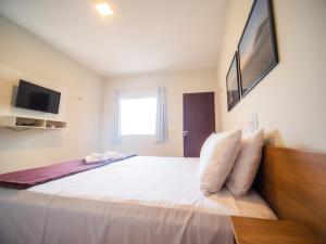 a bedroom with a large bed with white sheets at Pousada Reobote in São Miguel do Gostoso