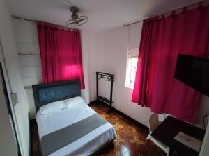 1 dormitorio con cortinas rojas, 1 cama y TV en Hotel Sion Real, en Neiva