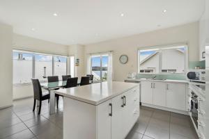 a kitchen with white cabinets and a table and chairs at Chapman Street Townhouse - walk beach & stadium in Bellerive