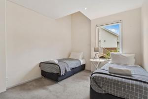 2 camas en una habitación con ventana en Chapman Street Townhouse - walk beach & stadium, en Bellerive