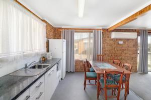 a kitchen with a sink and a table with chairs at Kellraine Holiday Units in St Helens