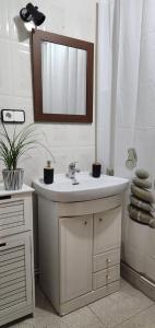 La salle de bains est pourvue d'un lavabo blanc et d'un miroir. dans l'établissement Casa de tres habitaciones con hermoso patio, à Puertollano
